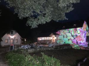 un muro coperto di graffiti accanto a una casa di notte di Mezriczky Malom Kapolcs a Kapolcs