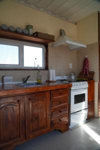 a kitchen with wooden cabinets and a sink and a stove at Casa container a 15km de Madryn in Puerto Madryn
