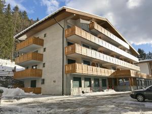a apartment building with wooden balconies and a parking lot at SISSI Apartment in Madonna di Campiglio