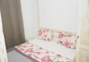 una piccola camera da letto con un letto con fiori rosa di Chez Ouly a Dakar