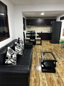 a living room with a black couch and a kitchen at Apartamentos Quimbaya in Quimbaya