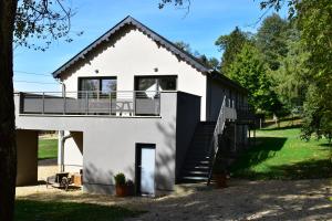 a white house with a balcony and stairs at Le gîte du Bois de Loo in Attert