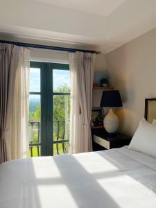 - une chambre avec un lit et une grande fenêtre dans l'établissement The Eyrie O1 Khao Yai, à Ban Bung Toei