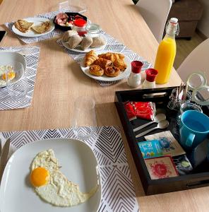 a table topped with plates of breakfast foods and orange juice at Les Chambres T4 in Huy