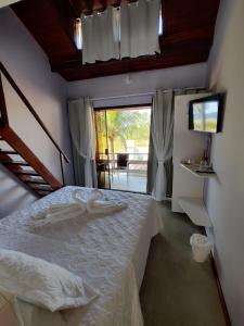 1 dormitorio con cama blanca y ventana en Pousada Sweet Home, en Búzios