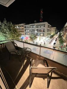 un balcón con 2 sillas y una mesa y un edificio en Modern apartment in the heart of the city, en Alexandroupoli