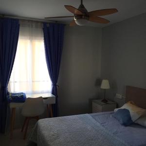 una camera con letto, ventilatore a soffitto e finestra di ALQUILO habitación en coqueto piso baño compartido a Torremolinos