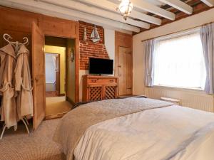 a bedroom with a bed and a television and a window at Driftwood Cottage in Harwich