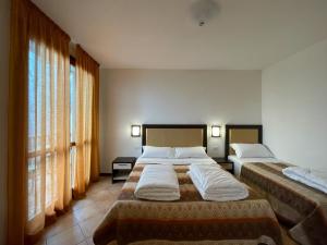 um quarto de hotel com duas camas e janelas em Residence le Polle em Riolunato