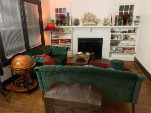 sala de estar con 2 sofás verdes y chimenea en Dr. Yaple's Art Deco House, en Lafayette