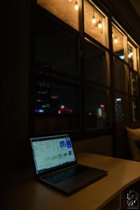 einem Laptop auf einem Tisch vor einem Fenster in der Unterkunft The Shack - Near Ben Thanh Market in Ho-Chi-Minh-Stadt