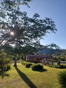 a house in the middle of a field with a tree at Fazenda do Engenho in Ritápolis