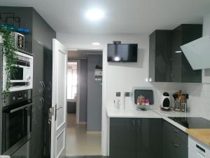 uma cozinha com armários pretos e bancadas brancas em Habitaciones Torremolinos em Torremolinos