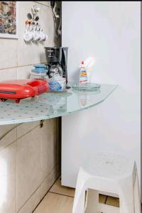 a glass counter in a kitchen with a stool at Quarto Suite - SAVASSI BH in Belo Horizonte