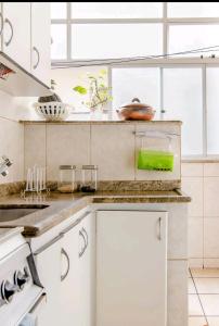 a kitchen with white cabinets and a counter top at Quarto Suite - SAVASSI BH in Belo Horizonte