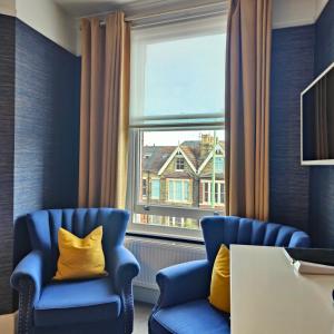 two blue chairs in a room with a window at The Corner House in Lowestoft