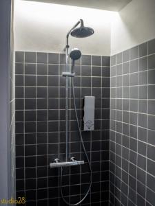 a black tiled shower with a shower head in a bathroom at Studio28 Boutique Rooms in Pärnu