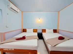 two beds in a room with red pillows on them at Peace Lanta Mansion in Ko Lanta