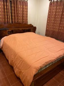 uma cama com um edredão laranja num quarto em สวนสน โฮมสเตย์ em Mae Hong Son
