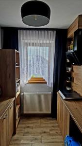 a kitchen with a window with a radiator and a curtain at Willa "KomaNcza" Szczawnica E-Apartamenty in Szczawnica