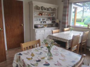 ein Esszimmer mit einem Tisch und einer Blumenvase darauf in der Unterkunft Drumgauty Cottage in Strabane