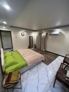 Un dormitorio con una cama verde y una silla en استراحة شرفة الواحةOasis Terrace Inn and Lounge, en Bahlāʼ