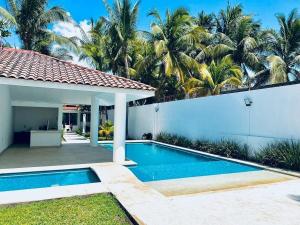 a swimming pool in the backyard of a house with palm trees at Casa Trébol: Tu Casa de Playa. Disfruta en familia in Puerto Arista