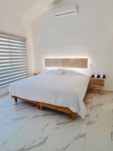 a white bedroom with a bed and a window at Casa Trébol: Tu Casa de Playa. Disfruta en familia in Puerto Arista