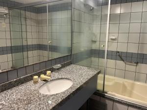 La salle de bains est pourvue d'un lavabo, d'un miroir et d'une baignoire. dans l'établissement Flat Iate Plaza, à Fortaleza