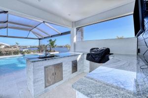a kitchen with a counter and a swimming pool at New listing - Amazing new 3beds/3baths Gulf access villa w. heated pool and outdoor kitchen! in Matlacha