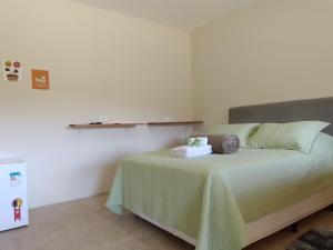 sypialnia z łóżkiem z zieloną narzutą w obiekcie Pousada Girassol 2 w mieście Poços de Caldas