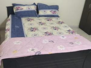 a bed with a pink comforter with flowers on it at Aayushman Homes in Bangalore