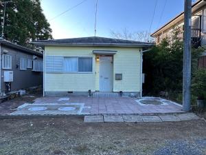 a small yellow house with a white door at Shirako House in Shirako
