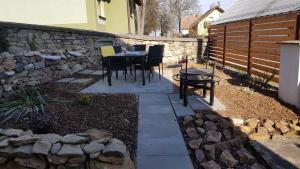 un patio con una mesa y una pared de piedra en Apartmán Dubovka, 