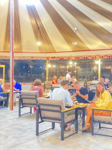 a group of people sitting at tables in a restaurant at Tamim Luxury wadi rum camp in Wadi Rum