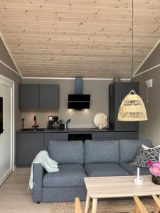 a living room with a blue couch and a kitchen at Kavliskogen panorama in Isfjorden