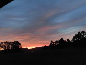 einen Sonnenuntergang über einem Feld mit Bäumen im Vordergrund in der Unterkunft Petit Chalet Nature in Les Rousses
