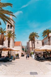 une rue dans une ville avec des palmiers et une tour de l'horloge dans l'établissement Apartments Filipo, à Trogir