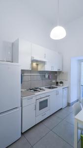 Casa Doclea _Comfort & relax nel cuore della città في نابولي: مطبخ بدولاب بيضاء وفرن علوي موقد