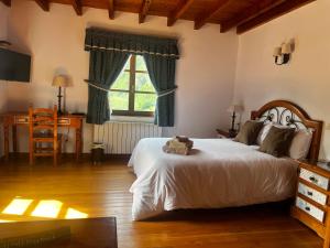 a bedroom with a bed and a desk and a window at Hotel Rural El Sestil in Dobres