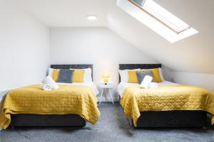 two beds in a attic room with yellow and blue at Modern Apartments Near Cardiff City Centre in Cardiff