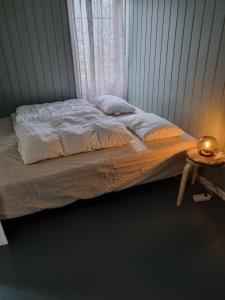 an unmade bed in a bedroom with a side table at Stor leilighet med 4 senger sentralt i Førde in Førde