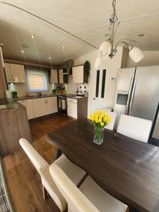 a kitchen with a wooden table with yellow flowers on it at Chillingham lodge with hot tub Felmoor Park in Felton