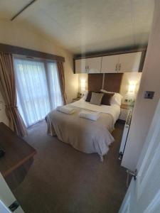 1 dormitorio con cama grande y ventana grande en Chillingham lodge with hot tub Felmoor Park, en Felton