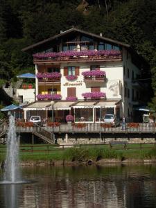 a building with flowers on the side of a lake at Miramonti Hotel in Garniga Terme