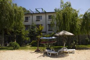 a patio with chairs and an umbrella and a building at Vila Raluca in Eforie Nord