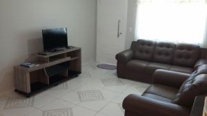 Casa Bombinhas temporada في بومبينهاس: غرفة معيشة مع أريكة وتلفزيون بشاشة مسطحة
