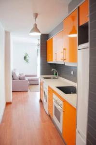 een keuken met oranje kasten en een fornuis met oven bij Apartamento Cerca del Mar y aeropuerto in Alicante