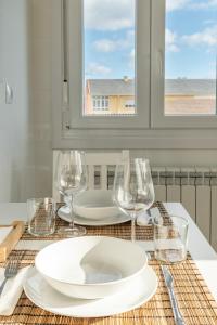 a table with a plate and wine glasses on it at Piso en el puerto con vistas al Mar+Wifi+ SmartTv in Burela de Cabo