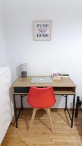 塞薩羅尼基的住宿－Comfort Corner 75m2 100Mbs，笔记本电脑前的一张带红色椅子的桌子